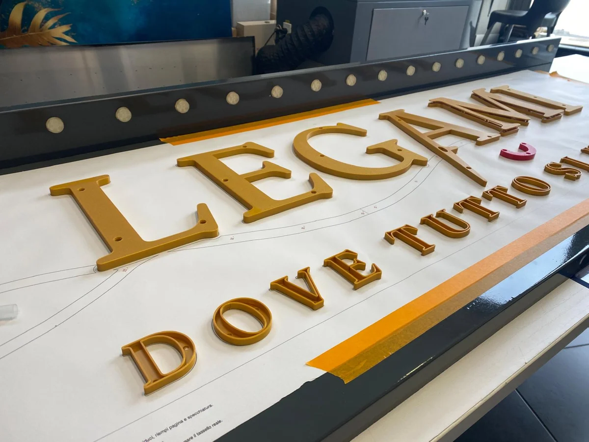 Lettere e segno grafico Legami con finitura oro durante la preparazione in laboratorio